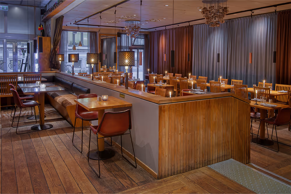 Wooden tables, leather seating and chandeliers in Belgobaren’s Stockholm dining room