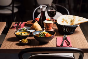 Indian dishes, naan bread and a glass of red wine on a set table at Happy India in Stockholm