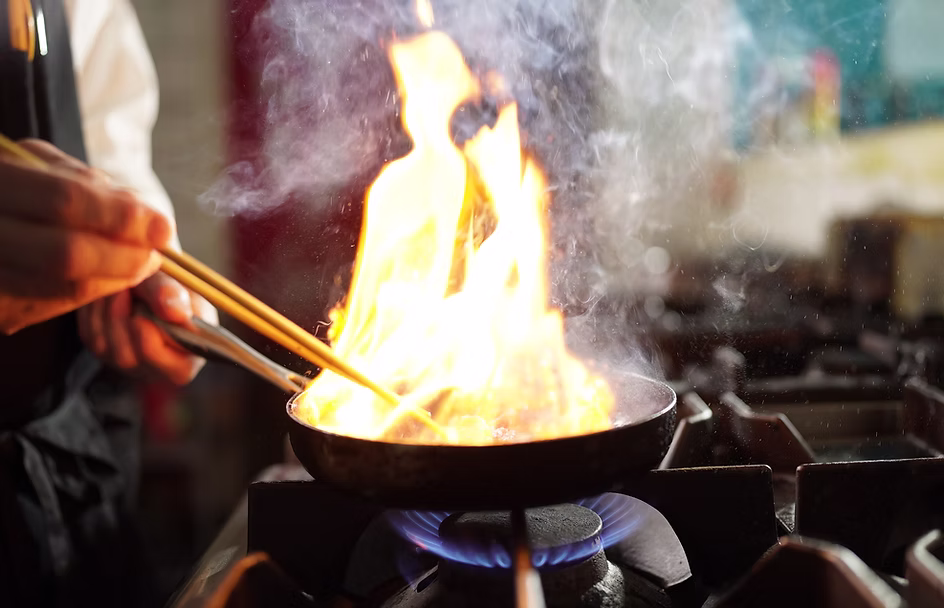 A chef cooking over flames in the kitchen at Blue Light Yokohama in Stockholm