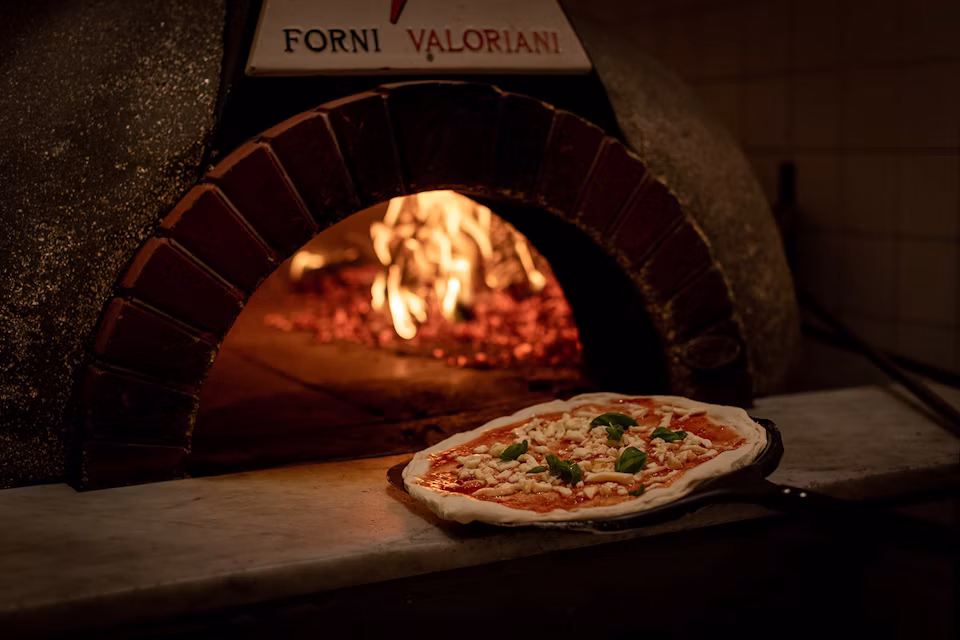 A pizza beside the glowing oven at Giro Pizzeria in Stockholm