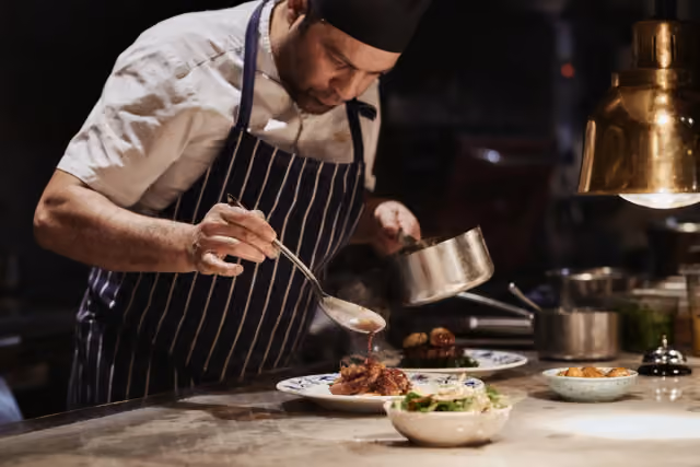 A chef plating a dish in Trattorian’s open kitchen in Stockholm